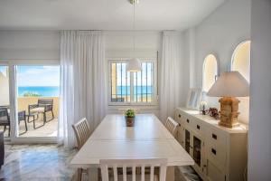 a dining room with a table and a view of the ocean at Beach View Playa Del Moral in Estepona