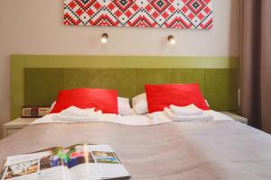łóżko z czerwonymi poduszkami i książką w obiekcie Hotel *** NAT Krynica Zdrój w mieście Krynica Zdrój