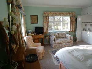 a bedroom with a bed and a chair and a window at The Newnham White House in Baldock