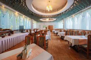 a dining room with tables and chairs and windows at Hotel *** NAT Krynica Zdrój in Krynica Zdrój