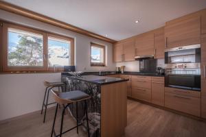 a kitchen with wooden cabinets and a island with bar stools at Chalet Brunner 2 in Wengen