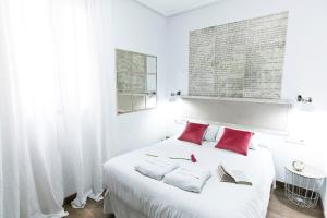 um quarto branco com uma grande cama branca com almofadas vermelhas em Vázquez de Mella Gran Vía em Madrid