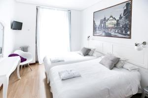 two beds in a white room with a desk and a window at Vázquez de Mella Gran Vía in Madrid