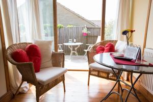 a living room with chairs and a table with a laptop at Heatherbell Cottage Guest Accommodation in West Bay