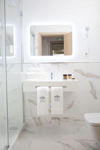 a white bathroom with a sink and a mirror at Mafra Hotel in Mafra