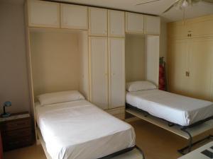 two beds in a room with white cabinets at Ducado - Fincas Arena in Benidorm +25 photos