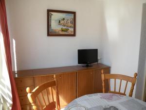 a tv sitting on top of a wooden dresser with a table at Ducado - Fincas Arena in Benidorm