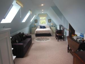 a bedroom with a bed and a couch in a attic at The Newnham White House in Baldock