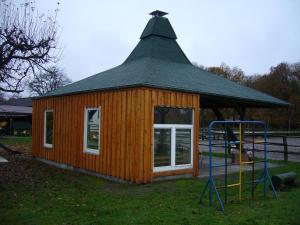 uma pequena cabana com um telhado de gambrel e um parque infantil em Ferienhof Drewes Ranch em Wietzendorf
