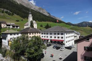 um grande edifício branco com uma torre de relógio numa montanha em Hôtel Bodenhaus em Splügen