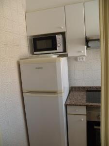 a white refrigerator with a microwave on top of it at Ducado - Fincas Arena in Benidorm