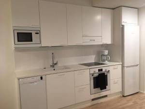 ユヴァスキュラにあるSonaatti Studio - best lake viewの白いキャビネット、シンク、冷蔵庫付きのキッチンが備わります。