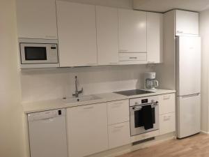 a kitchen with white cabinets and a sink and a refrigerator at Sonaatti Studio - best lake view in Jyväskylä