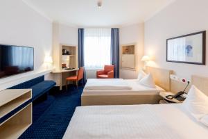 a hotel room with two beds and a television at IntercityHotel Magdeburg in Magdeburg +18 photos
