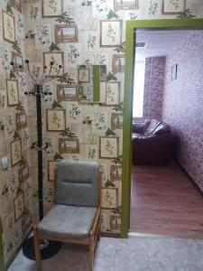 Zimmer mit einem Stuhl und einer Wand mit Bildern in der Unterkunft Apartament Erfolg 11 in Daugavpils