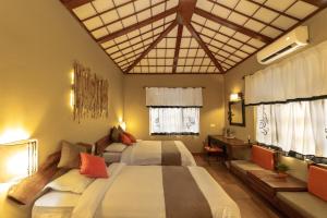 a bedroom with two beds and a desk and windows at Green Mansions Jungle Resort in Sauraha