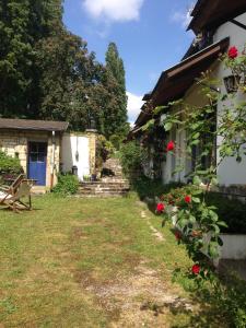 una casa con un patio al lado de un edificio con rosas rojas en Longère de charme, à 40 MN du Stade de France - Joli hameau, calme, cheminée, en Esches