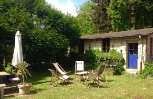 a group of chairs and a table and an umbrella at Longère de charme familiale pour un WE au coin du feu Joli hameau, calme, cheminée in Esches