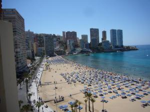 a beach with umbrellas and crowds of people at Carolina - Fincas Arena in Benidorm