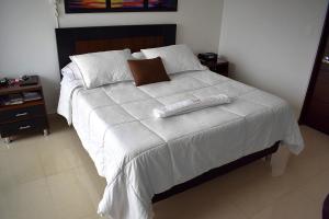a bed with a white comforter and two towels on it at Hotel Sophia Real in Yopal