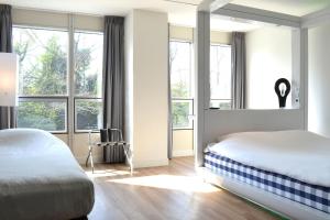 a bedroom with large windows and a bed with white sheets at Qbic Amsterdam WTC in Amsterdam