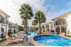 a pool with chairs and palm trees in a yard at Aparthotel Serena Dream in La Serena