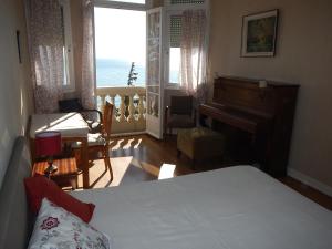 マントンにあるLe Reginaのベッドルーム1室(ベッド1台、ピアノ、デスク付)