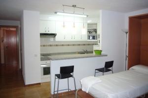 a kitchen with a bed and two chairs in a room at Las Palmeras III- Fincas Arena in Benidorm