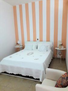 ein Schlafzimmer mit einem weißen Bett und einer gestreiften Wand in der Unterkunft Casa Martina in Peschici