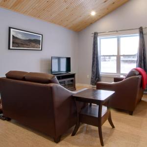 a living room with two couches and a table and a tv at Appalachian Chalets & RV in Corner Brook