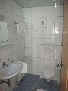 a white bathroom with a toilet and a sink at Gasthof Hirschen in Wenns