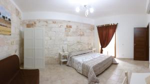 1 dormitorio con cama y pared de piedra en Ape Rossa, en Castellana Grotte