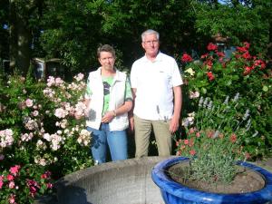 two people are standing in a garden with flowers at Mehr -Nordseeurlaub in Butjadingen