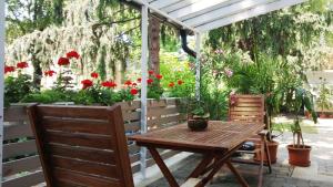 a patio with a wooden table and two chairs and flowers at Tisch Vendégház in Hajdúszoboszló