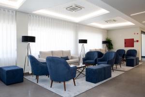 a waiting room with blue chairs and a couch at Mafra Hotel in Mafra