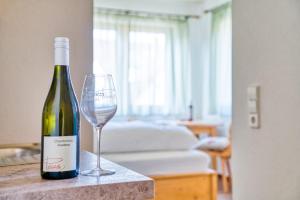 una botella de vino y una copa de vino en una mesa en Gästehaus Weingut Politschek en Bad Friedrichshall