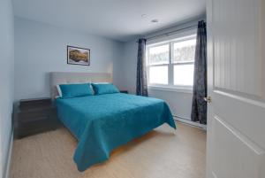 sypialnia z łóżkiem z niebieską narzutą i oknem w obiekcie Appalachian Chalets & RV w mieście Corner Brook
