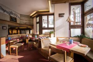 a restaurant with wooden tables and chairs and windows at Hotel La Collina in Saas-Fee