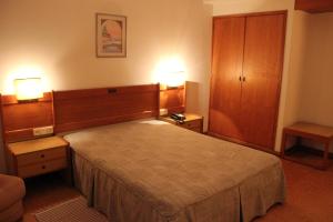 Vila de PradoにあるHotel Bom Sucessoのベッドルーム1室(大型ベッド1台、ナイトスタンド2台付)