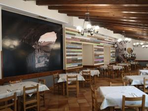 une salle à manger avec des tables, des chaises et un grand écran dans l'établissement Ostatu Zegama, à Zegama