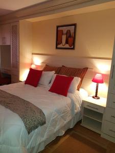 a bedroom with a large white bed with red pillows at Ocean View Villas Unit G02 in Port Edward