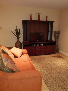 sala de estar con sofá naranja y TV de pantalla plana en Ocean View Villas Unit G02, en Port Edward