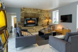 a living room with couches and a stone fireplace at Villa Marine in Plouguin