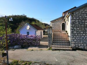a small house with purple flowers next to a building at Rustic village in Rijeka Crnojevića