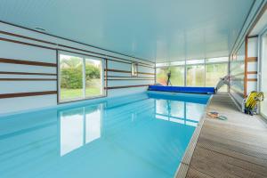 a swimming pool in a house with blue ceilings at Villa Marine in Plouguin