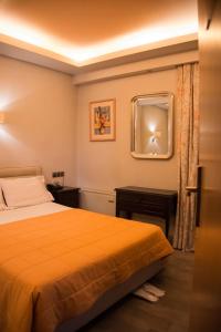 Schlafzimmer mit einem Bett und einem Wandspiegel in der Unterkunft Hotel Maroussi in Athen