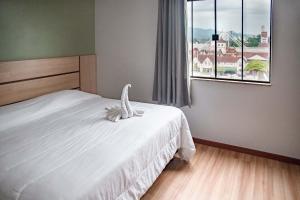 1 dormitorio con cama blanca y ventana en Blu Terrace Hotel, en Blumenau