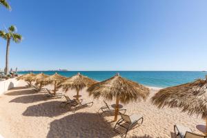 a row of straw umbrellas and chairs on a beach at Sonoran Sea 3BR Deluxe SSE 608 by Casago in Puerto Pe&ntilde;asco