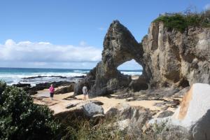 people standing on the beach near a rock formation at Narooma Motel in Narooma