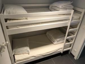 ein weißes Etagenbett mit weißen Kissen und Handtüchern in der Unterkunft Residentie Sorrento in Middelkerke